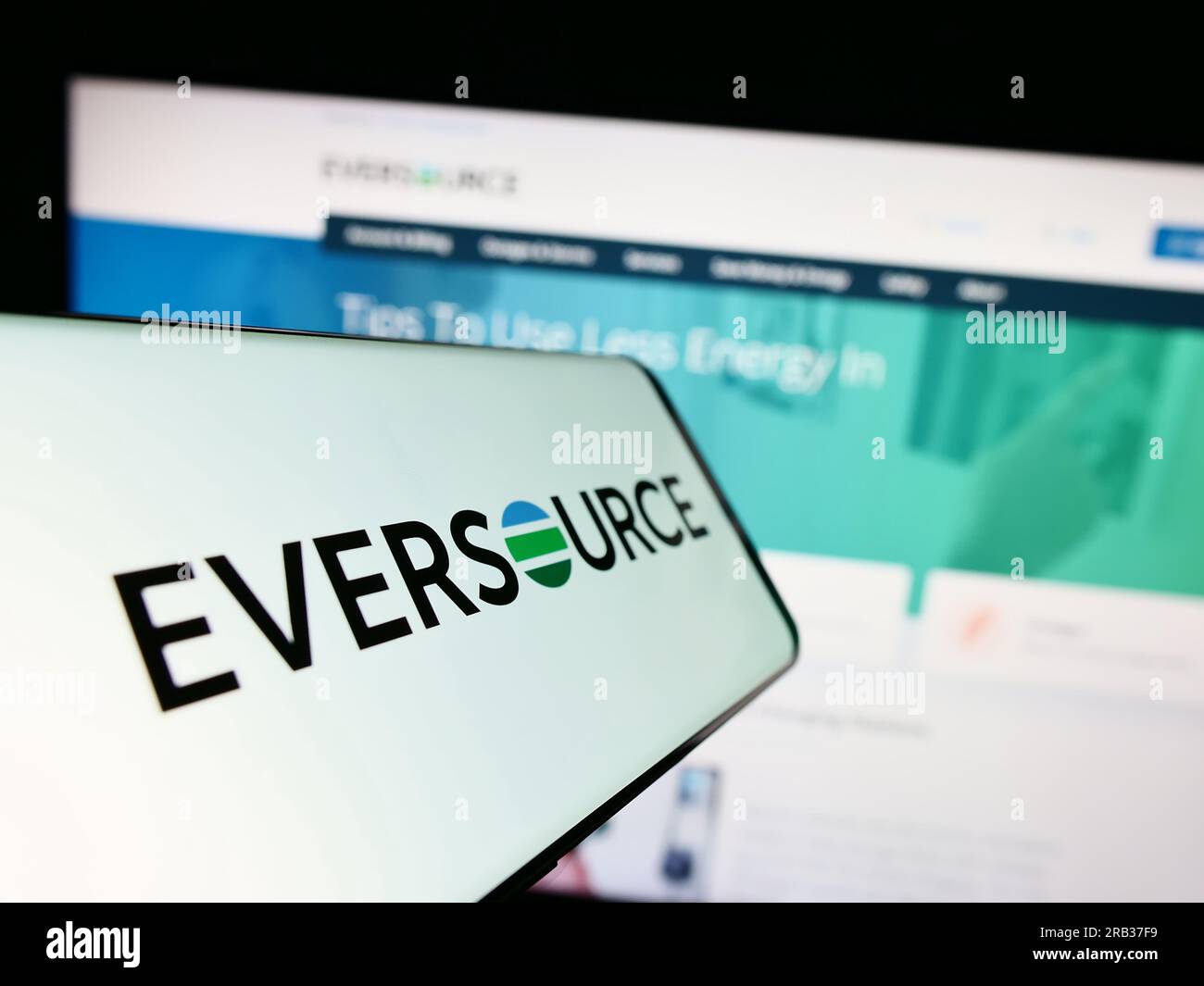 Cellphone with logo of American utility company Eversource Energy on screen in front of website. Focus on center-right of phone display. Stock Photo
