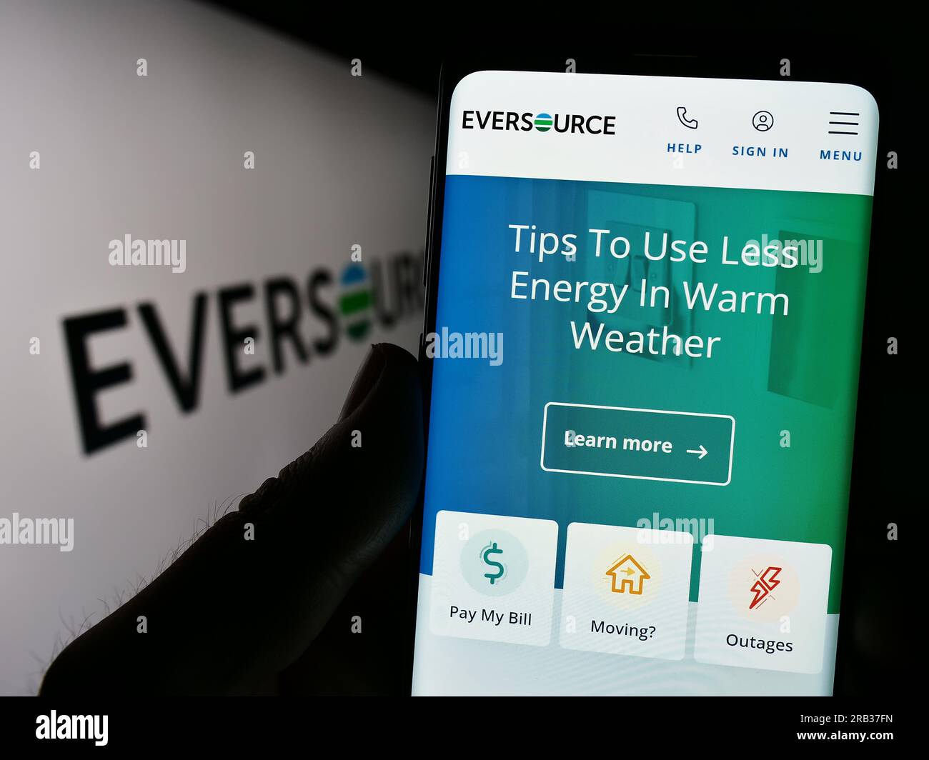 Person holding smartphone with website of US utility company Eversource Energy on screen in front of logo. Focus on center of phone display. Stock Photo