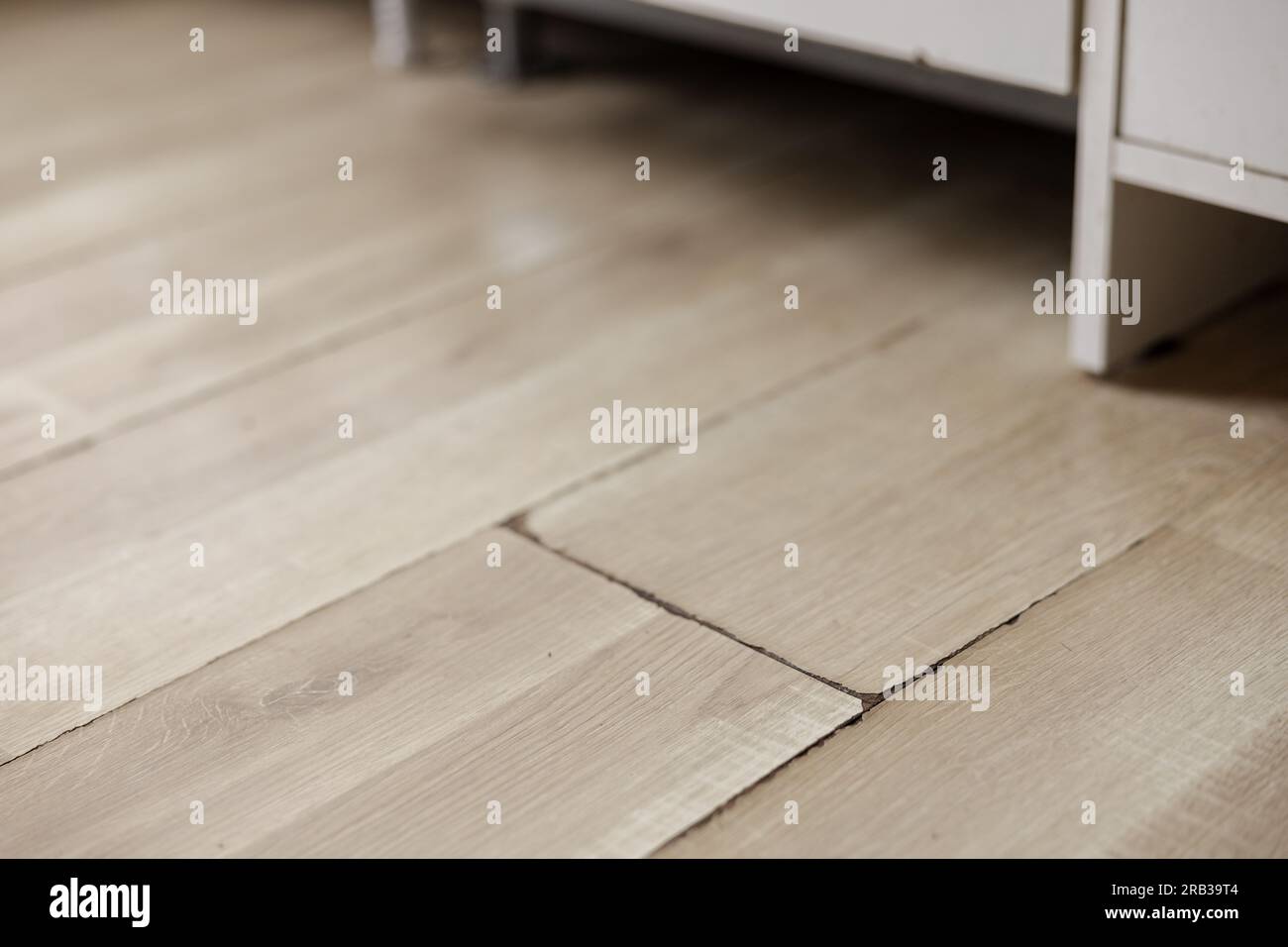 Swollen and dirty laminate floor, close up view. Moisture damage