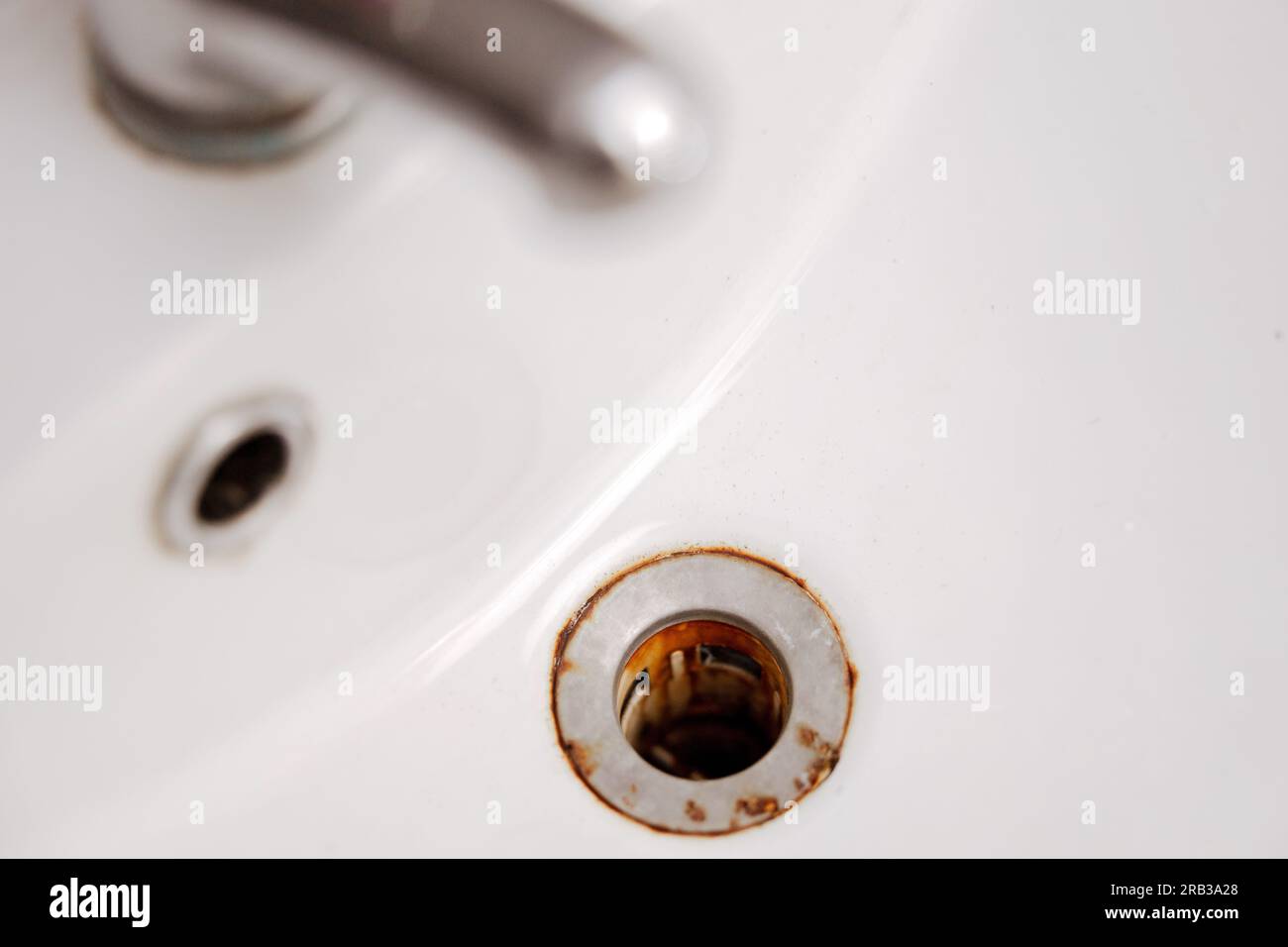 Dirty and rusty washbasin, close up view. Metal drain hole with red