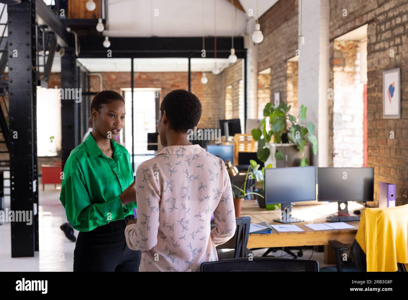 Busy african american female colleagues discussing work in creative office. Business, brainstorm and teamwork, unaltered. Stock Photo