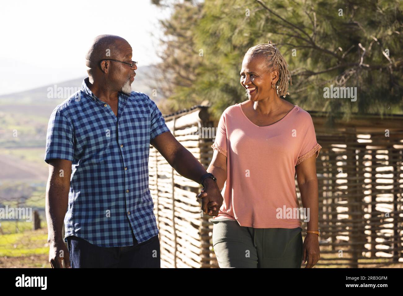 Happy senior african american couple holding hands and walking in sunny ...