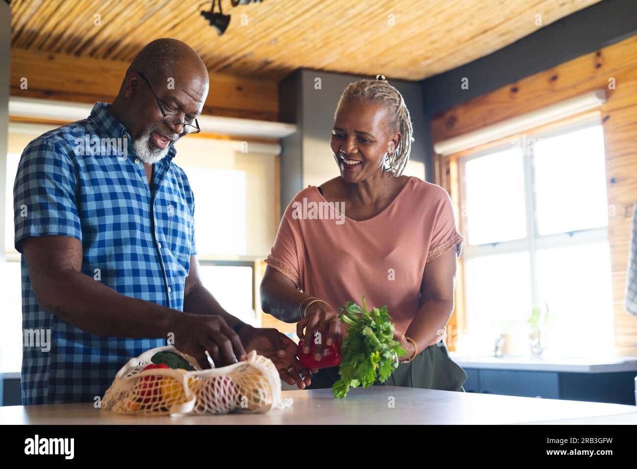 Happy senior african american couple unpacking groceries in kitchen ...