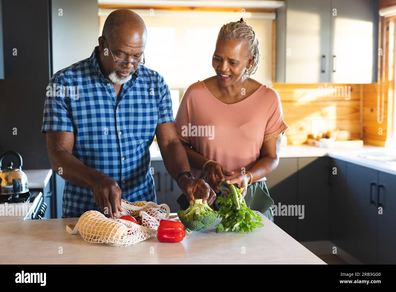Happy senior african american couple unpacking groceries in kitchen ...