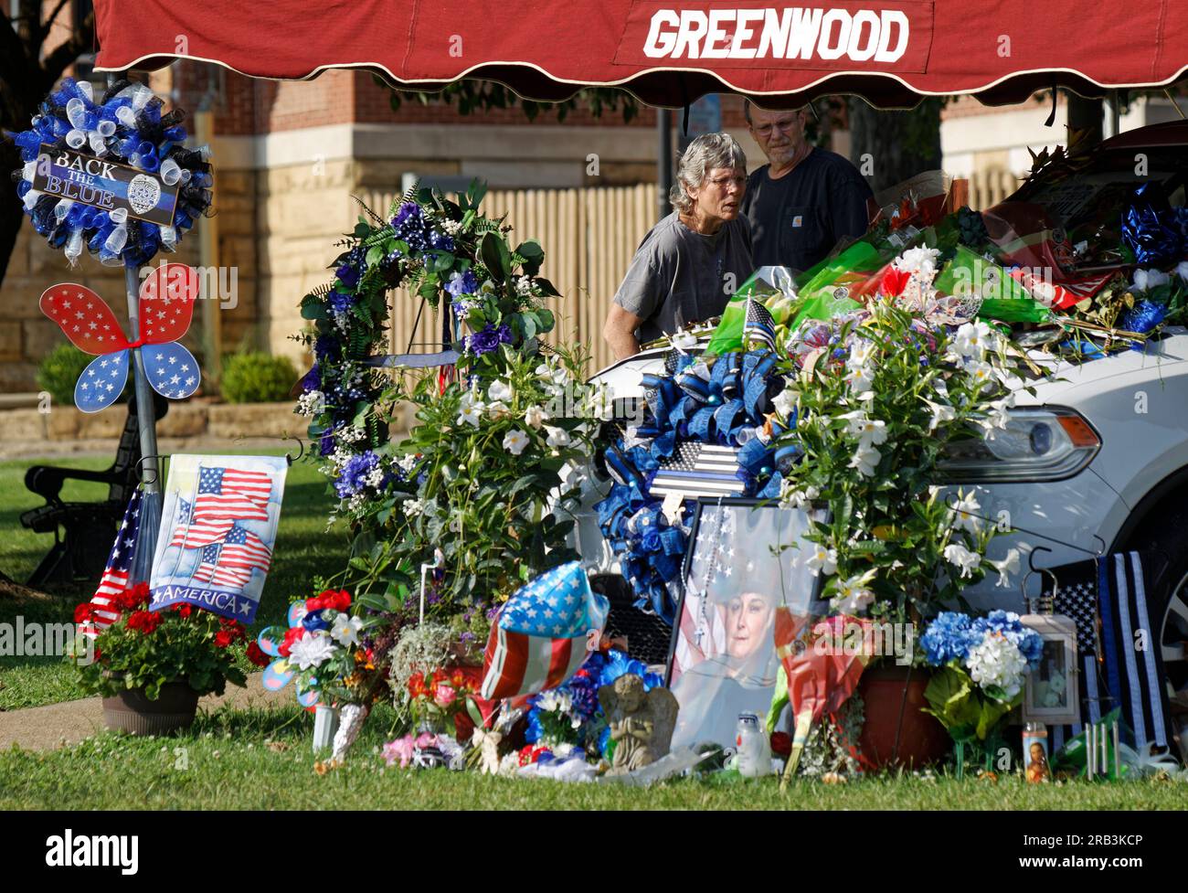 A pair of visitors examine flowers and memorial tributes piled on and around the Dodge Durango patrol vehicle of Tell City Police Department Sgt. Heather J. Glenn on Thursday, July 6, 2023 near city hall in Tell City, Troy Township, Perry County, IN, USA. Glenn, 47, was shot and killed July 3 while trying to arrest a domestic violence suspect at a local hospital, becoming the first line-of-duty death in the Tell City Police Department's nearly 165-year history and second Indiana police officer to be killed in the line of duty in less than a week. (Apex MediaWire Photo by Billy Suratt) Stock Photo