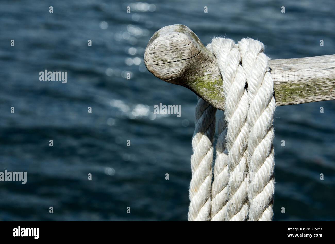 Wood rod with mooring rope hanging over the water in the summer. Stock Photo