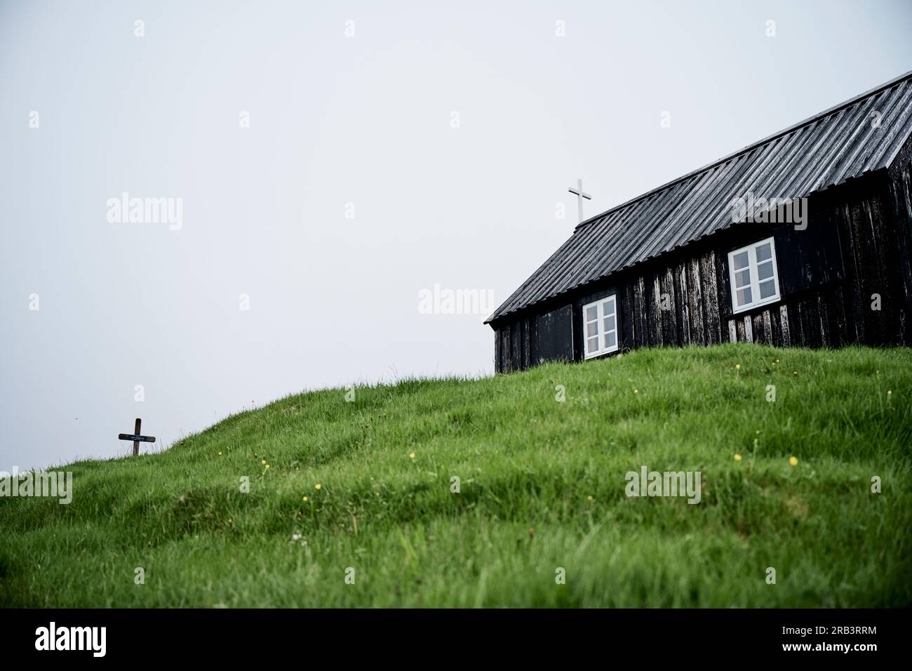 Aged church with cross on grassy meadow Stock Photo