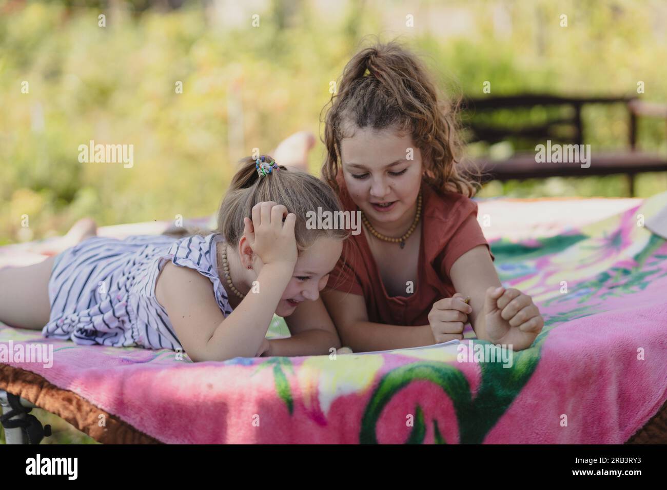 two preteen girls are relaxing in the summer garden behind the house Stock Photo