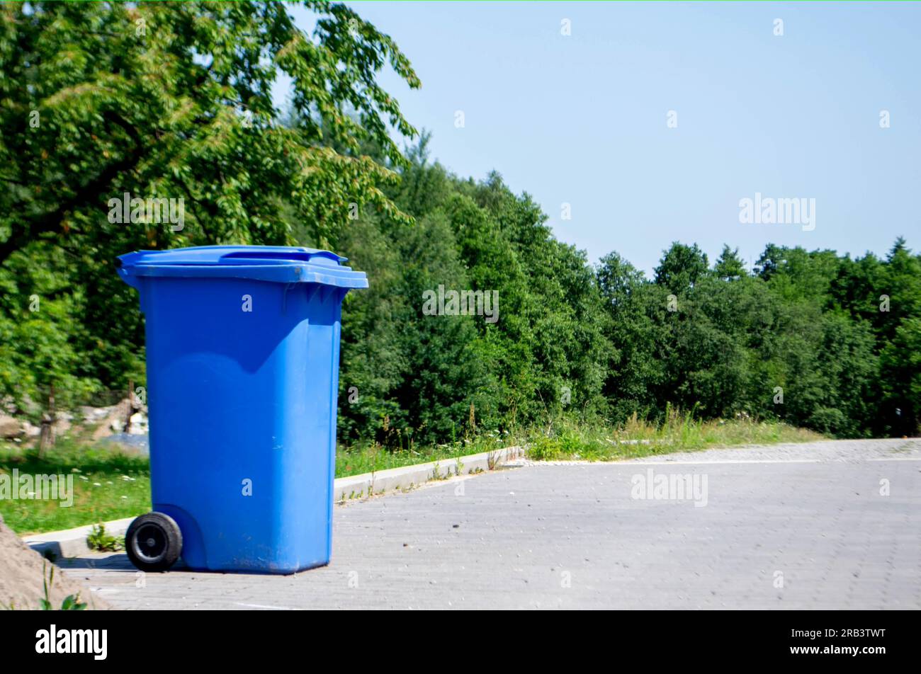 Unloocked big empty blue plastic trash garbage bin in front of the