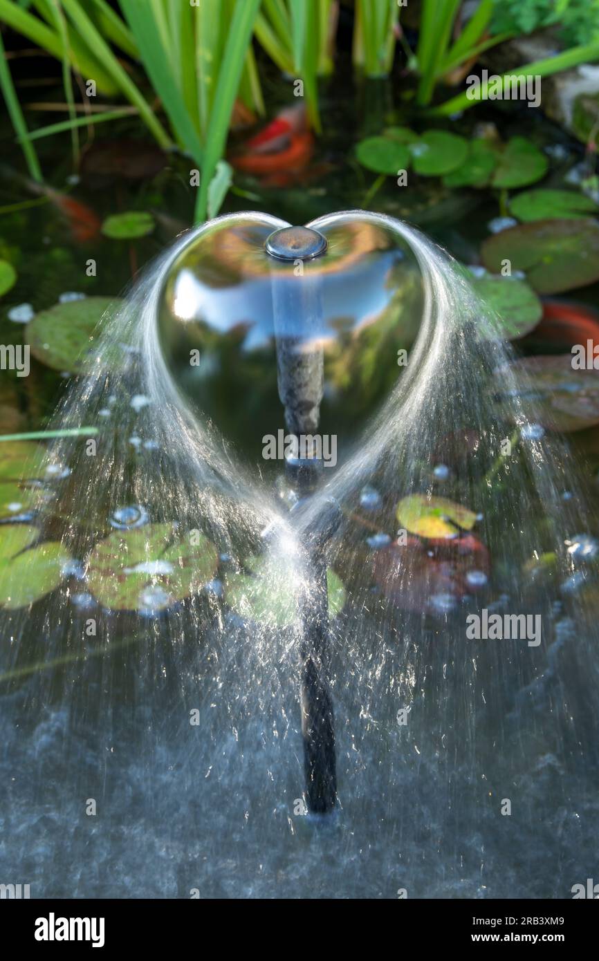 Fish pond water fountain in the shape of a heart. UK Stock Photo
