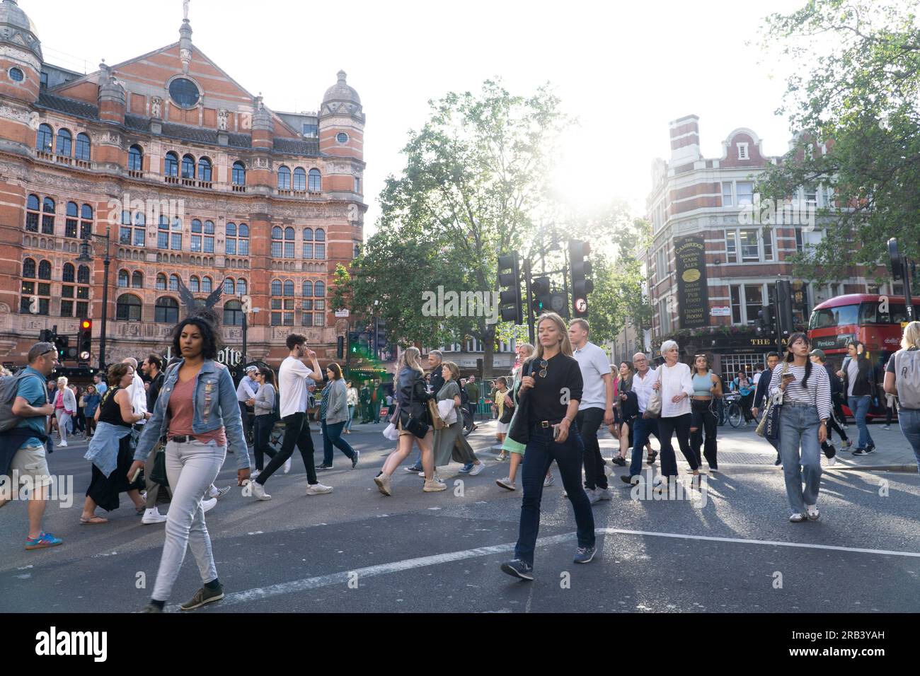 UK weather, 6 July 2023, London: After a few colder than average days, warm weather returns to London, bringing crowds into Soho. At Cambridge Circus people cross the road, each seeming oblivious to the others. Credit: Anna Watson/Alamy Live News Stock Photo