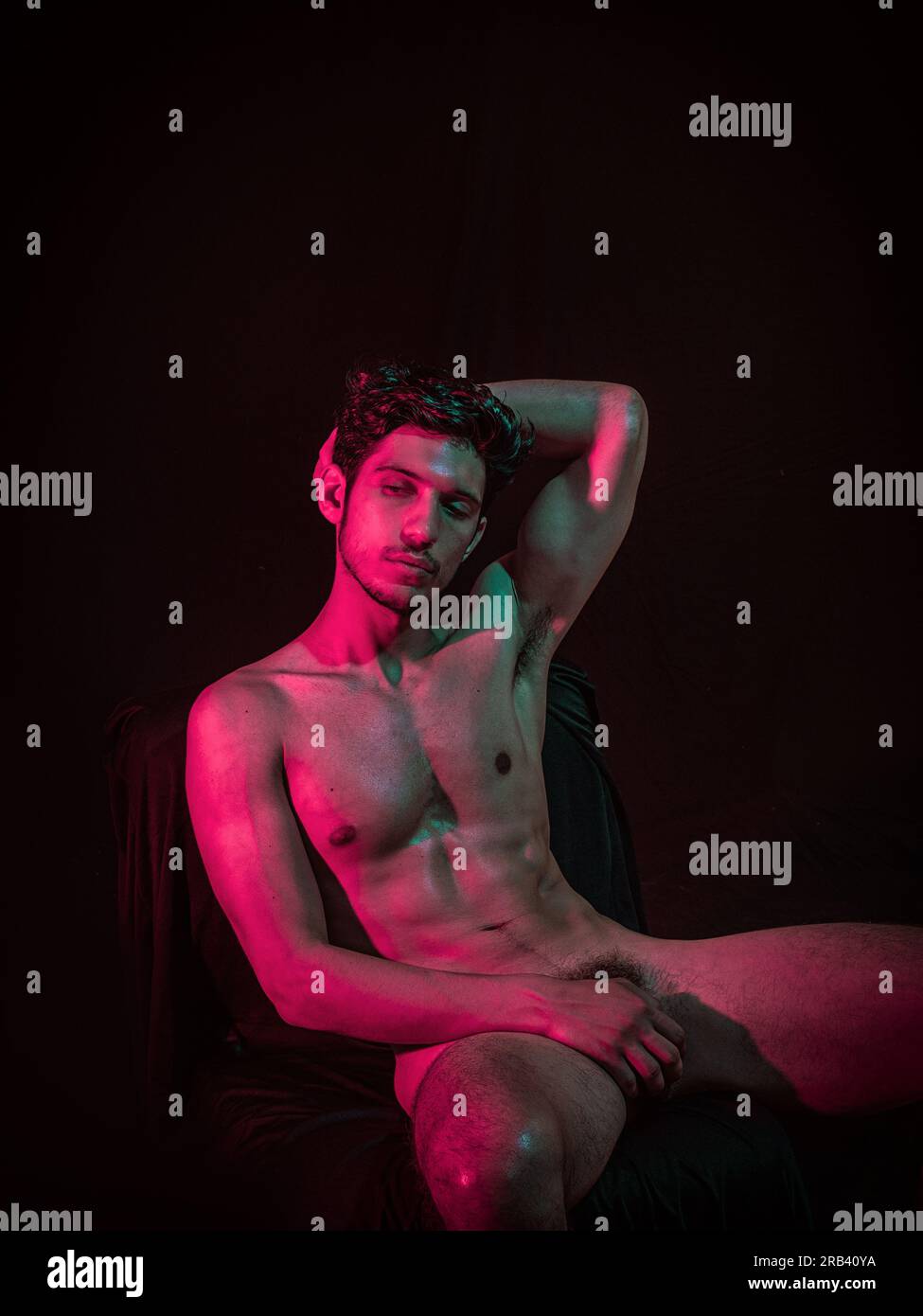 Totally naked athletic handsome young man, hiding genitals with hands,  looking away, on dark background in studio. A studio setting with a dark  backgr Stock Photo - Alamy