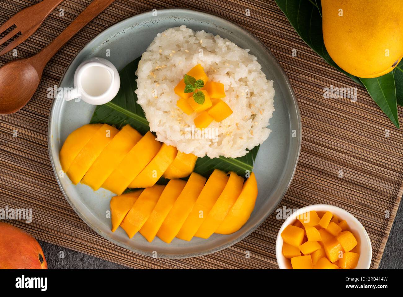 Delicious Thai mango sticky rice with cut fresh mango fruit in a plate on gray table background. Stock Photo