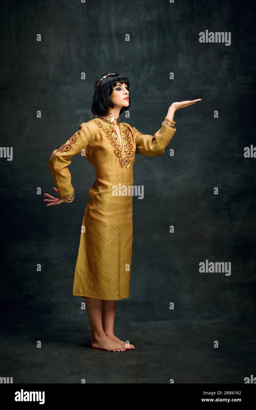 Portrait of young woman in golden dress, egyptian queen Cleopatra posing against dark vintage background. Royal person Stock Photo - Alamy Portrait of young woman in golden dress, egyptian queen Cleopatra posing against dark vintage background. Royal person Stock Photo - Alamy