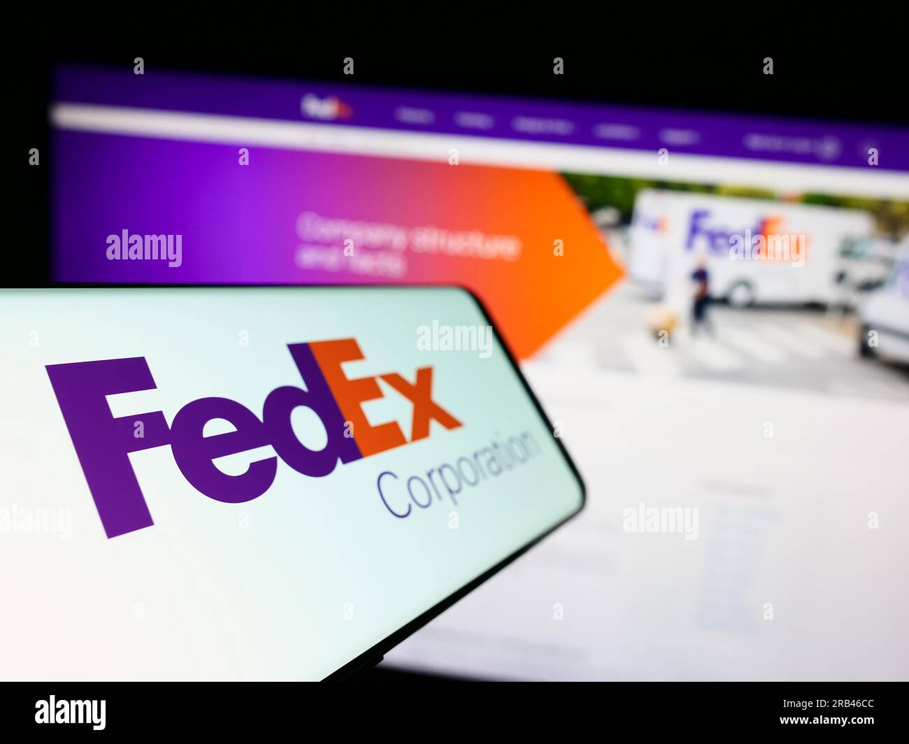 Mobile phone with logo of American logistics company FedEx Corporation on screen in front of business website. Focus on left of phone display. Stock Photo