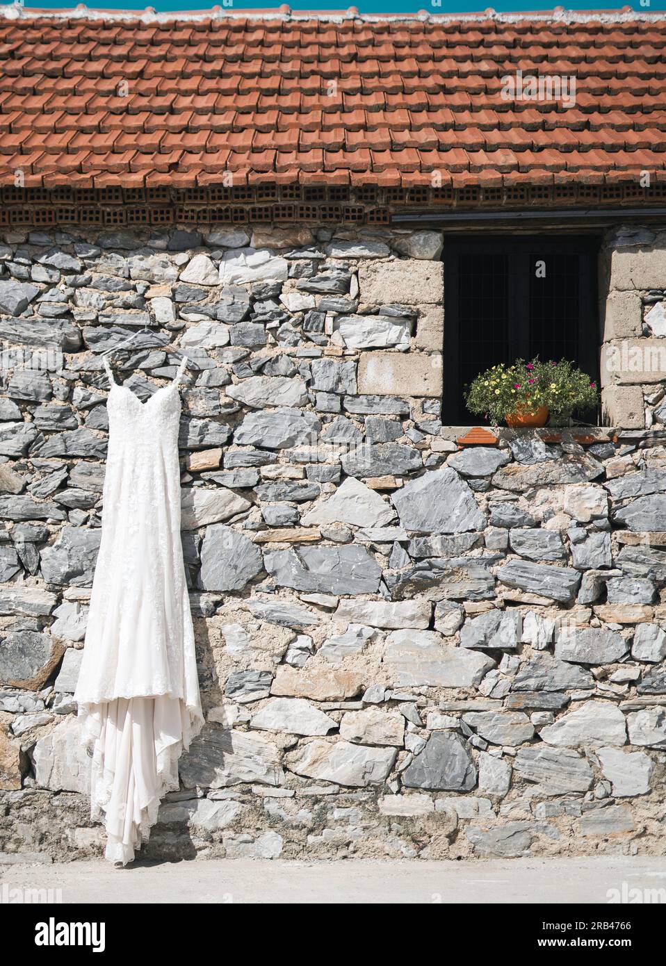 Ein wundervolles Hochzeitskleid hängt an einer traditionellen Steinwand Stock Photo