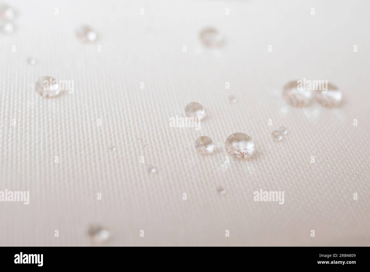 Clear water drops on white canvas, soft focus close up Stock Photo