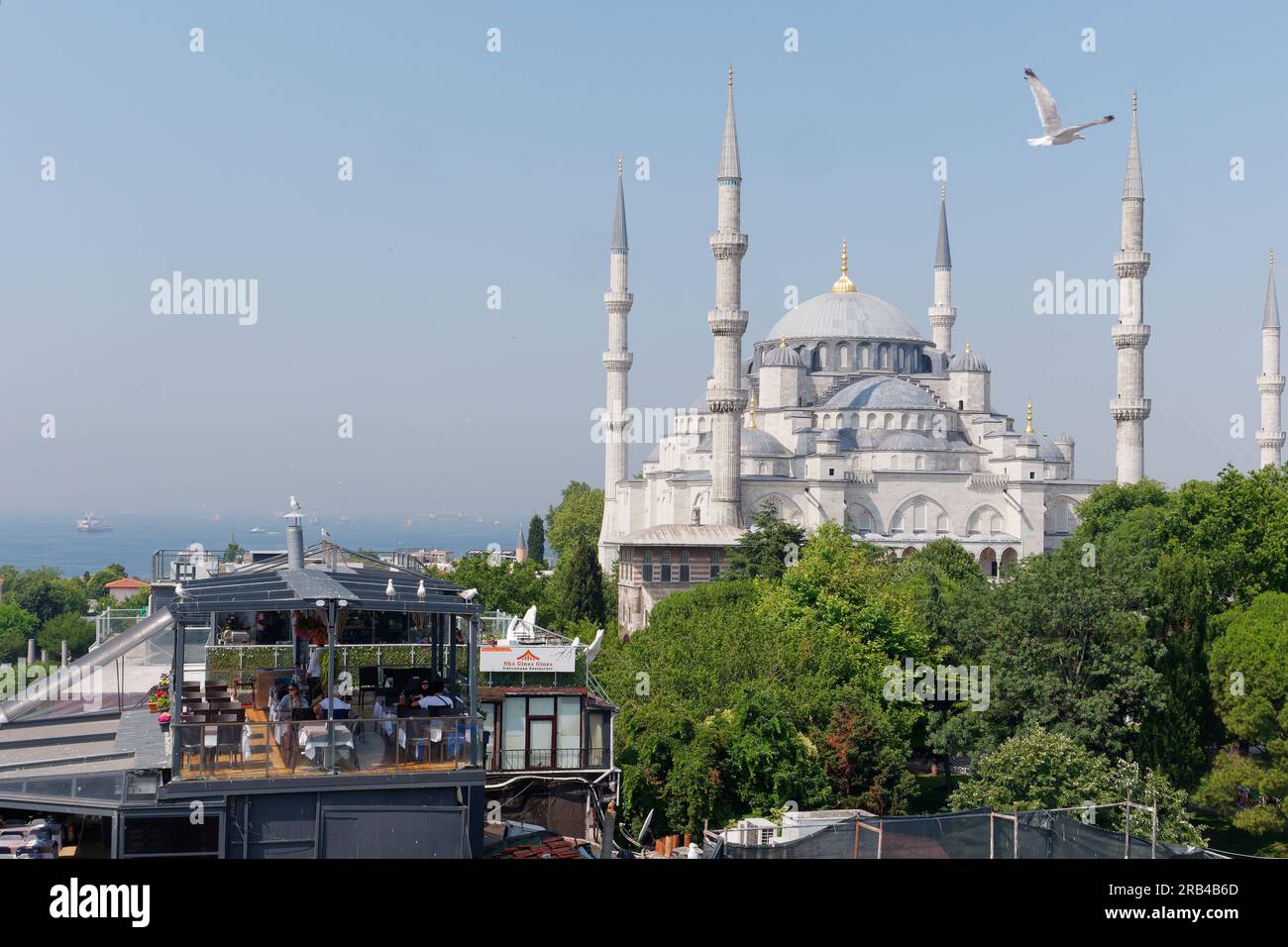 Elevated view of the Sultan Ahmed Mosque aka Blue Mosque. People dine at nearby restaurant with the Sea of Marmara behind, Istanbul, Turkey Stock Photo