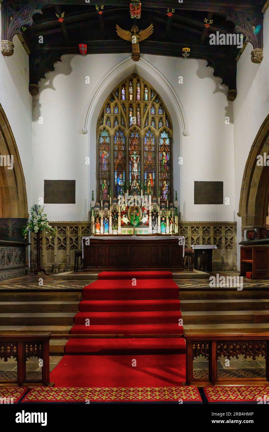 Skipton, North Yorkshire, England's Holy Trinity Church, as seen down its isle, complete with a red carpet and a spectacular stained glass window. Stock Photo