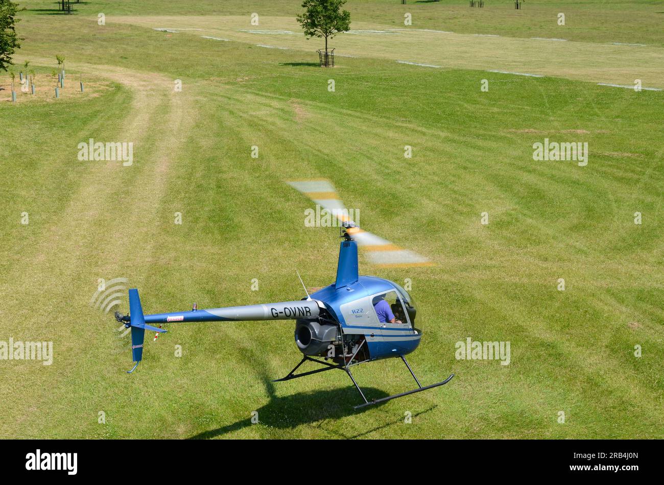 Robinson R-22 hovering low over grass airstrip at a wings and wheels event in the countryside at Heveningham Hall. Rural country in Suffolk Stock Photo