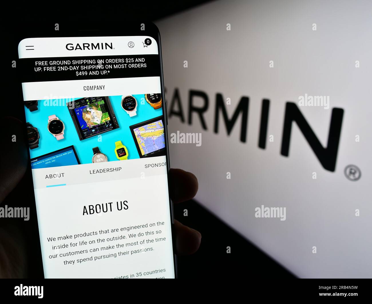 Person holding cellphone website logo of technology company Garmin Ltd. on screen in front of business logo. Focus on center of phone display. Stock Photo