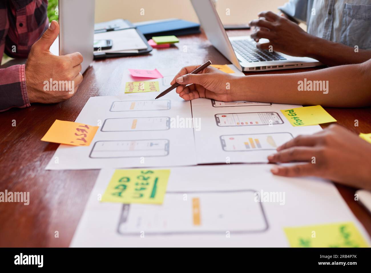 Close up of hands writing notes on mobile app layout design, coding ...