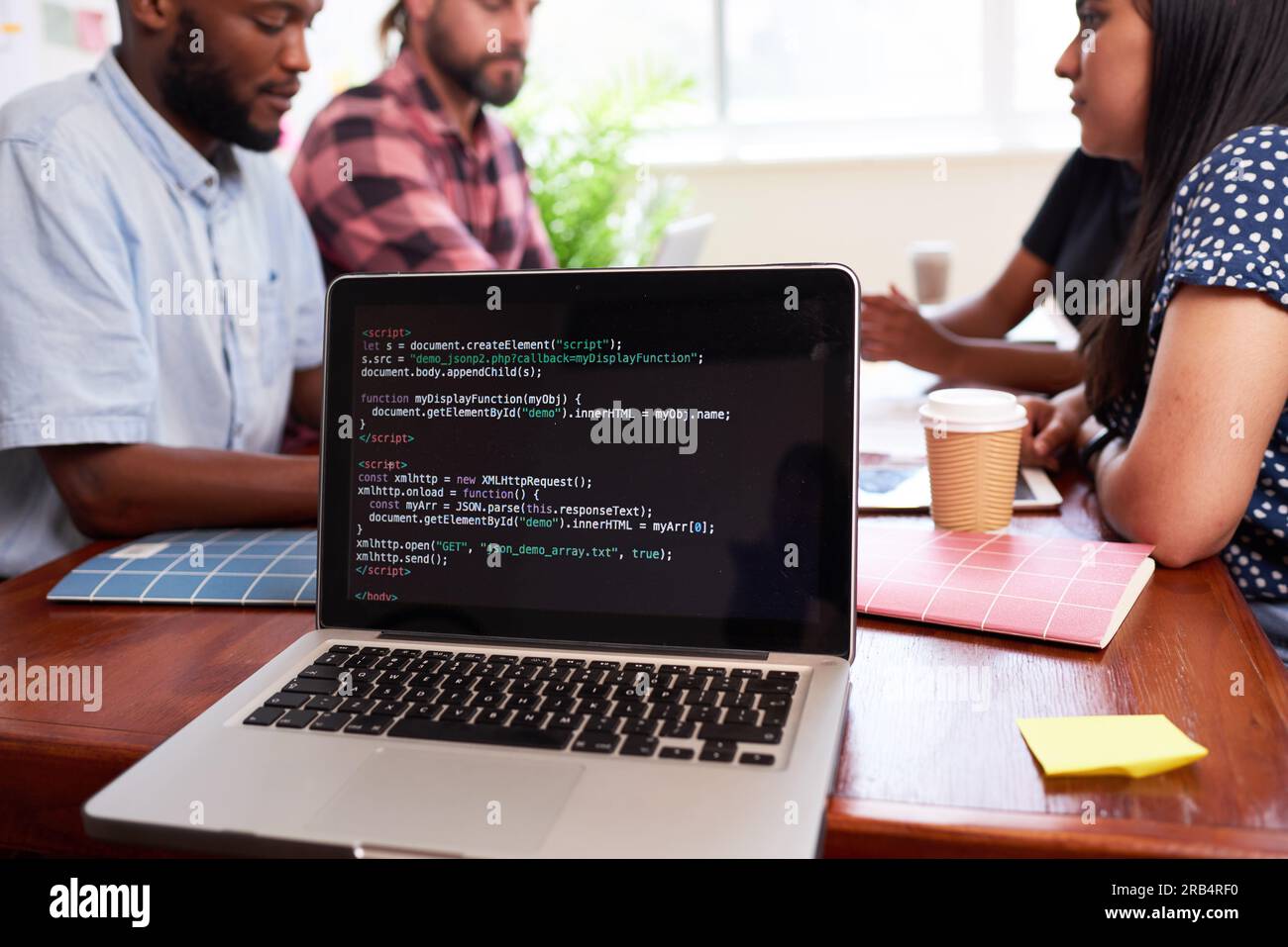 Close up of laptop screen with code, developers meeting boardroom table talking Stock Photo