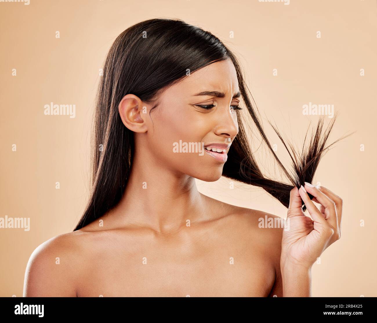 Woman, worry and split end in studio, background and beauty concern of hair loss, problem and damage. Stress, face and indian female model check tips Stock Photo