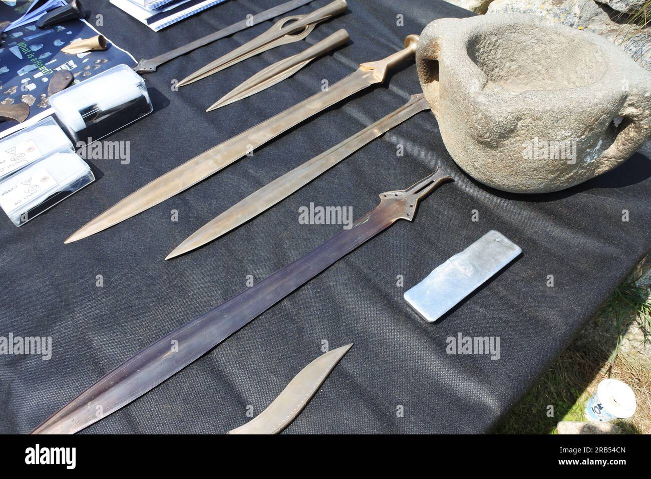Reproduction bronze age swords, daggers and knives at a finds table at an archaeological dig at St. Michael's Mount, Cornwall, UK - John Gollop Stock Photo