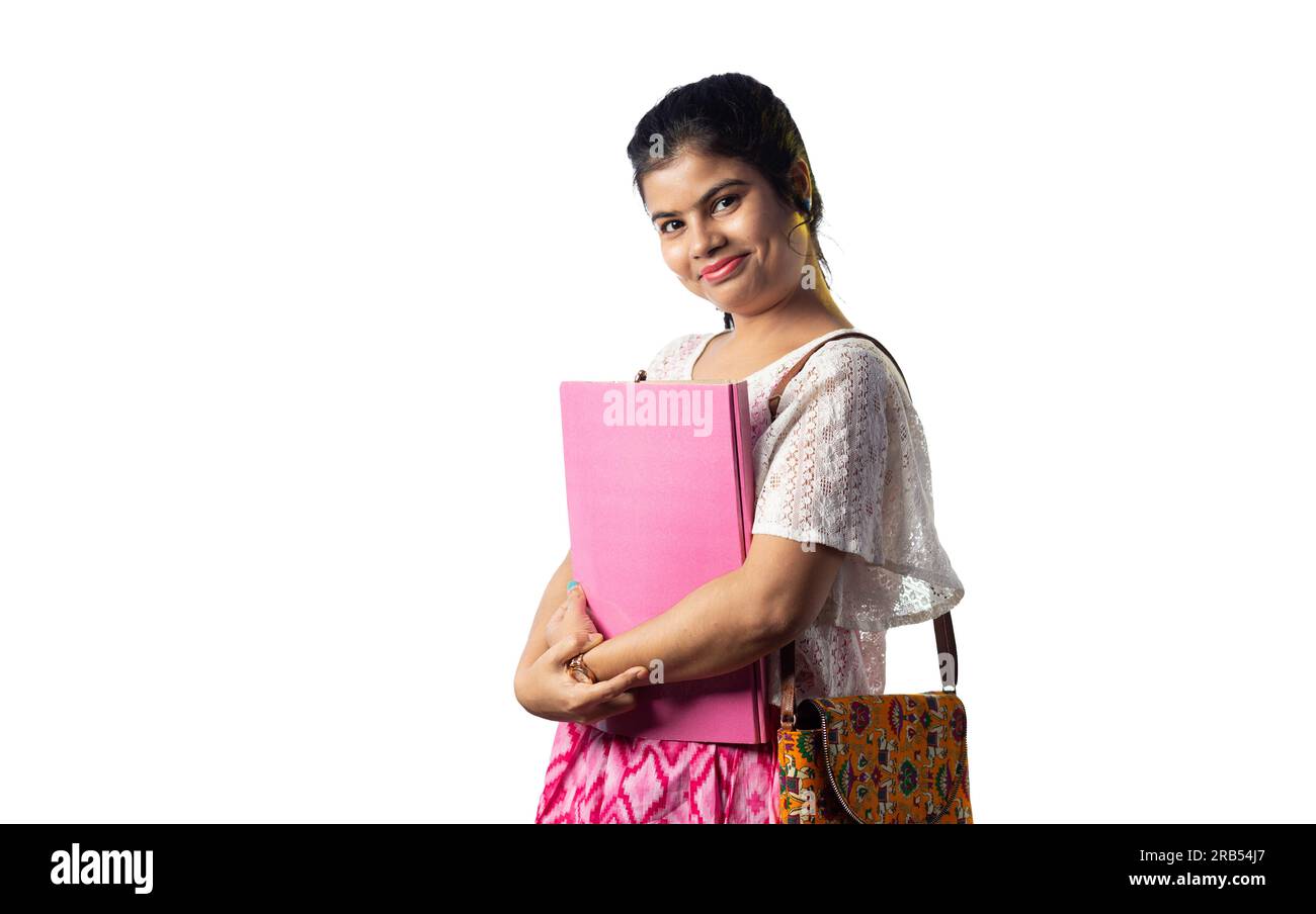 A pretty young Indian girl with books in hand standing with smiling ...