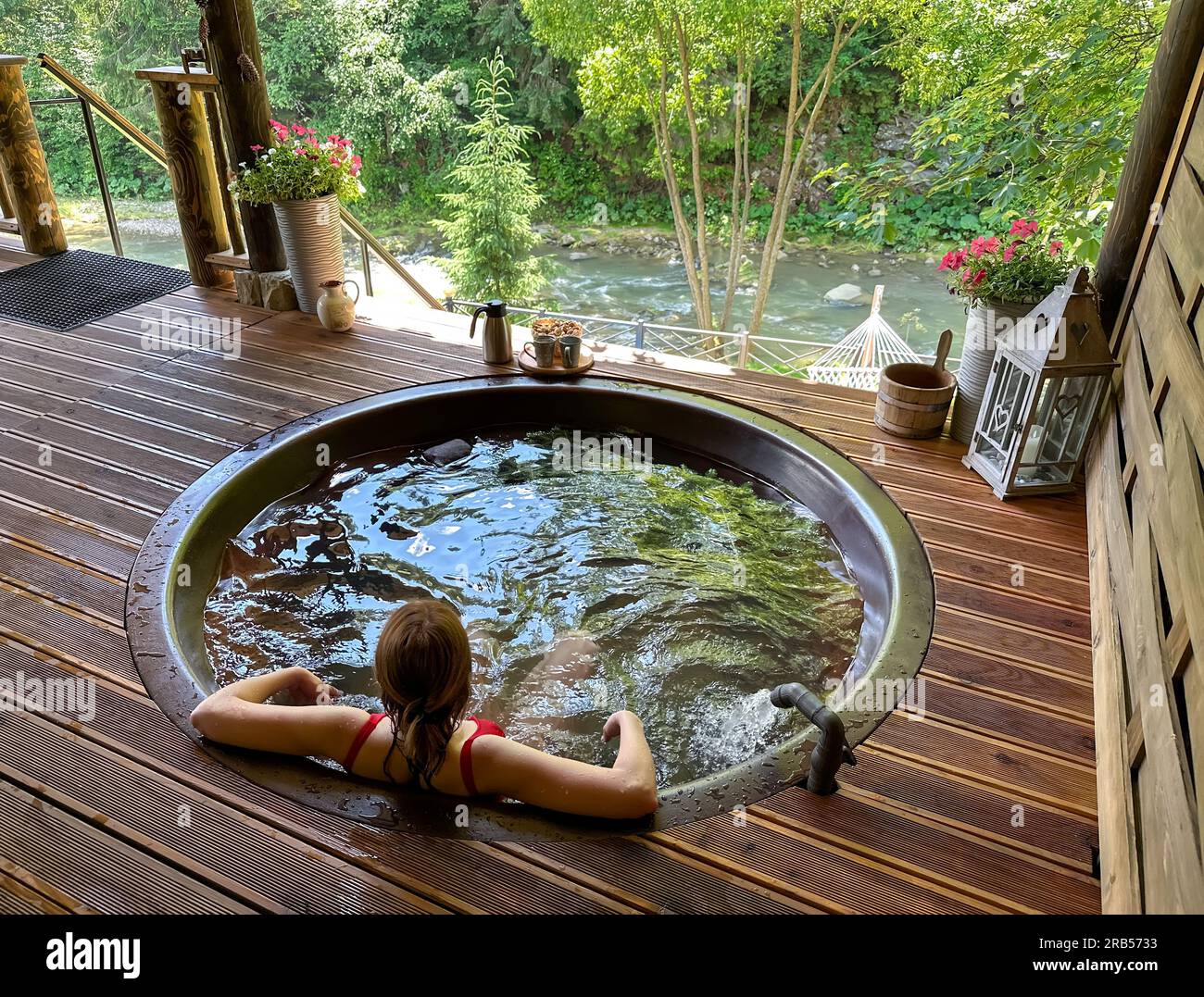 The girl bathes in a traditional iron hot tub against the backdrop of a