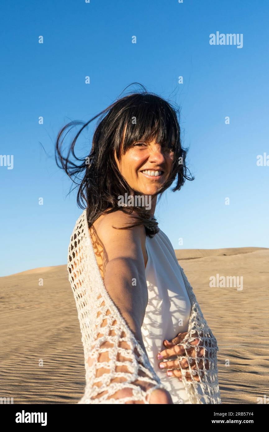 Follow me concept. A smiling long hair woman walking on the sand holding someone's hand. Stock Photo
