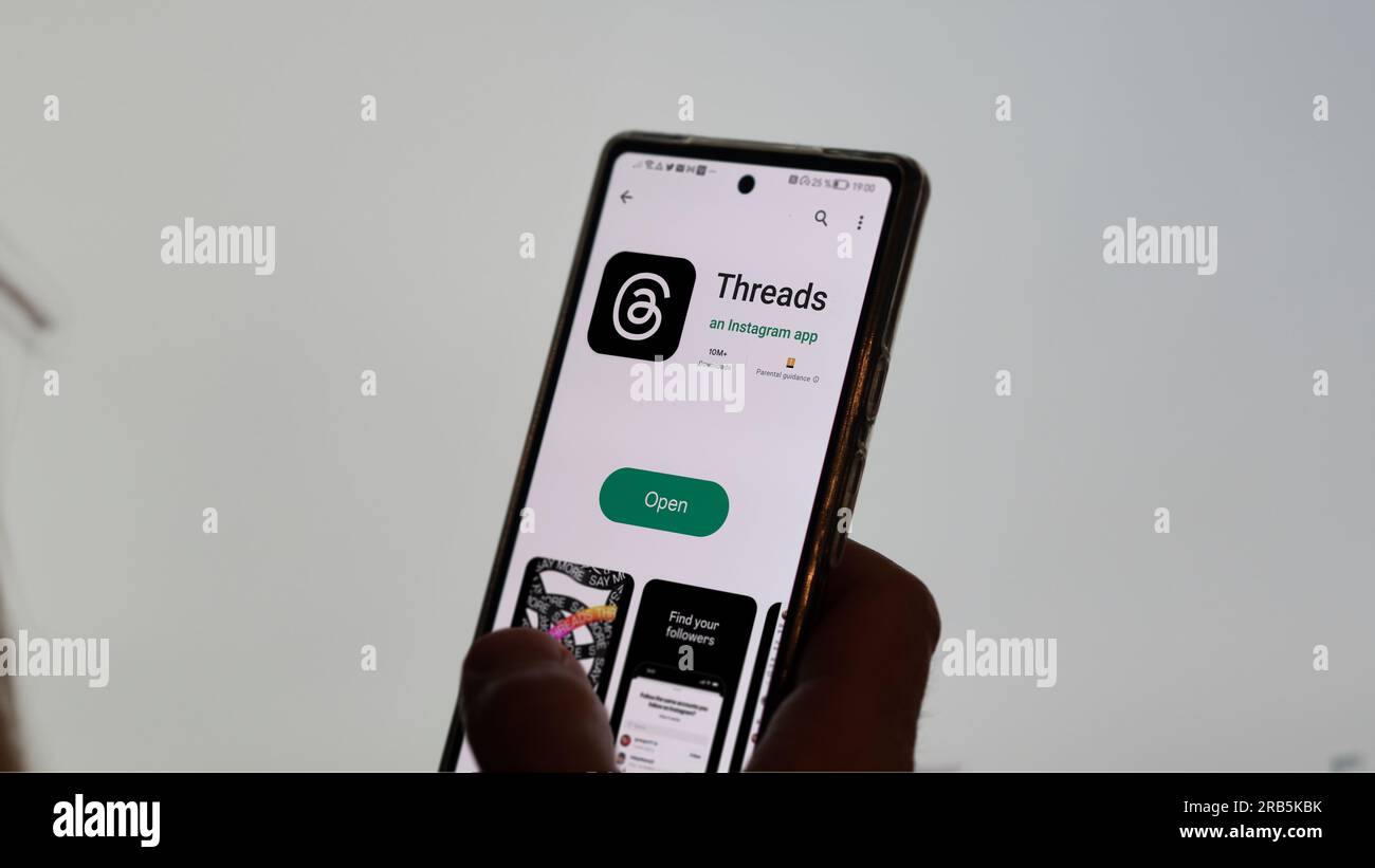 July 7th 2023, a hand holding a phone, the logo of Threads on the screen. On the background the blurry logo of Twitter. Stock Photo