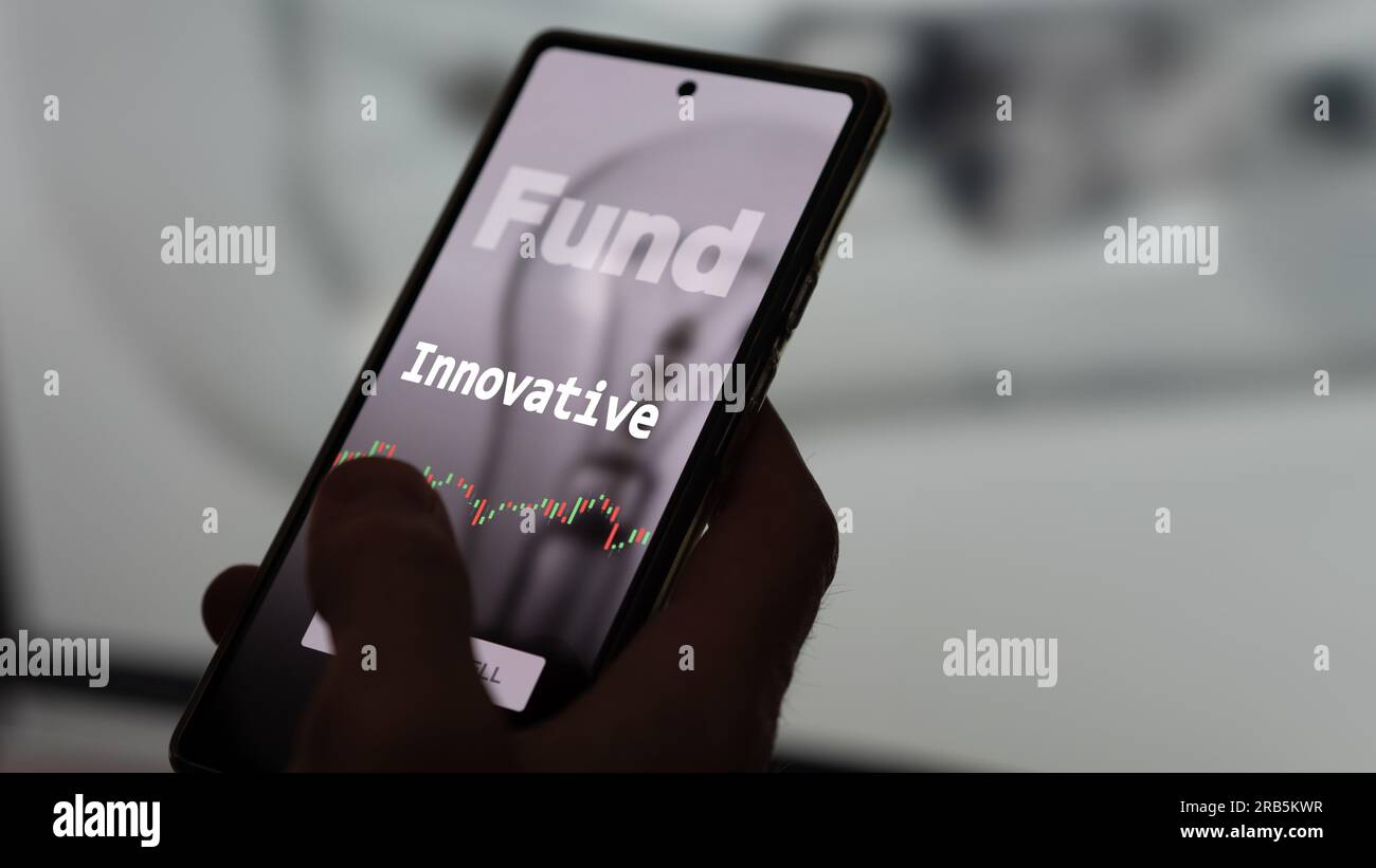 An investor's analyzing the innovation etf fund on a screen. A phone shows the prices of Innovation Stock Photo