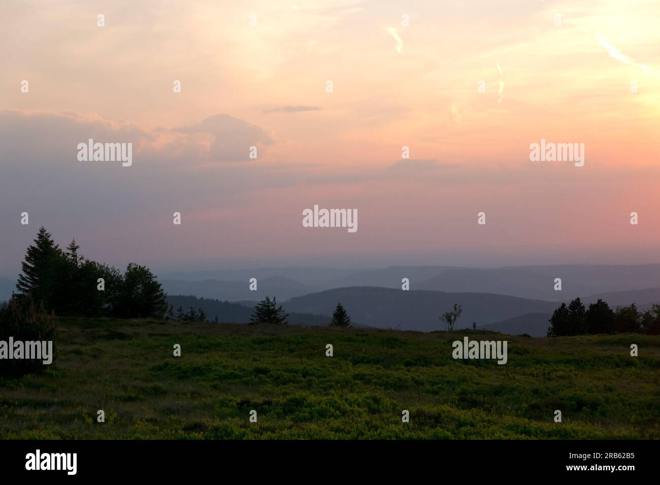 Hilly landscape shortly after sunset: silhouettes of hills under an orange-yellow colored sky Stock Photo