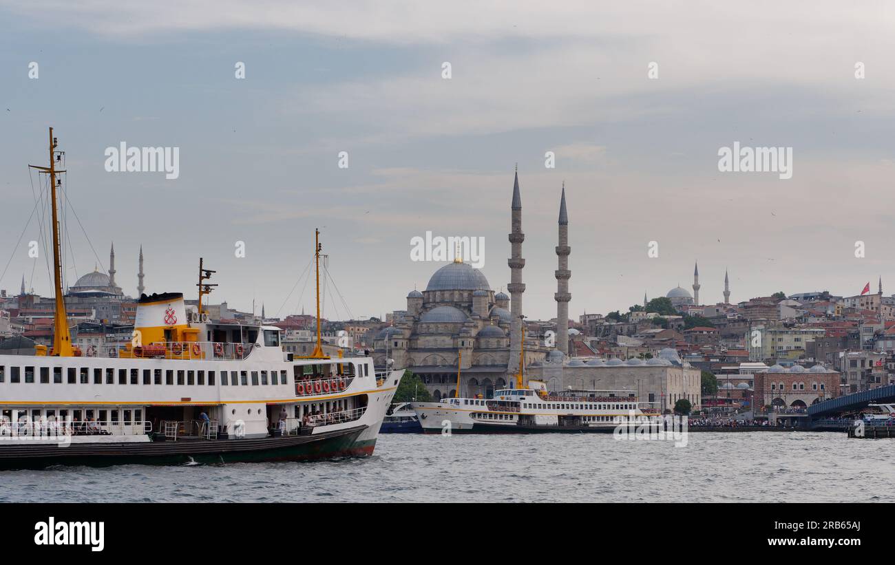 Passenger ferries on the Golden Horn River on a summers evening with the Yeni Cami Mosque or New Mosque centre. Istanbul, Turkey Stock Photo