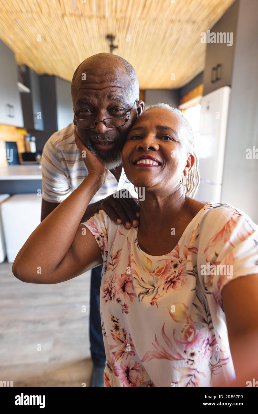 Happy senior african american couple making video call at home. Senior lifestyle, relaxing, retirement and communication, unaltered. Stock Photo
