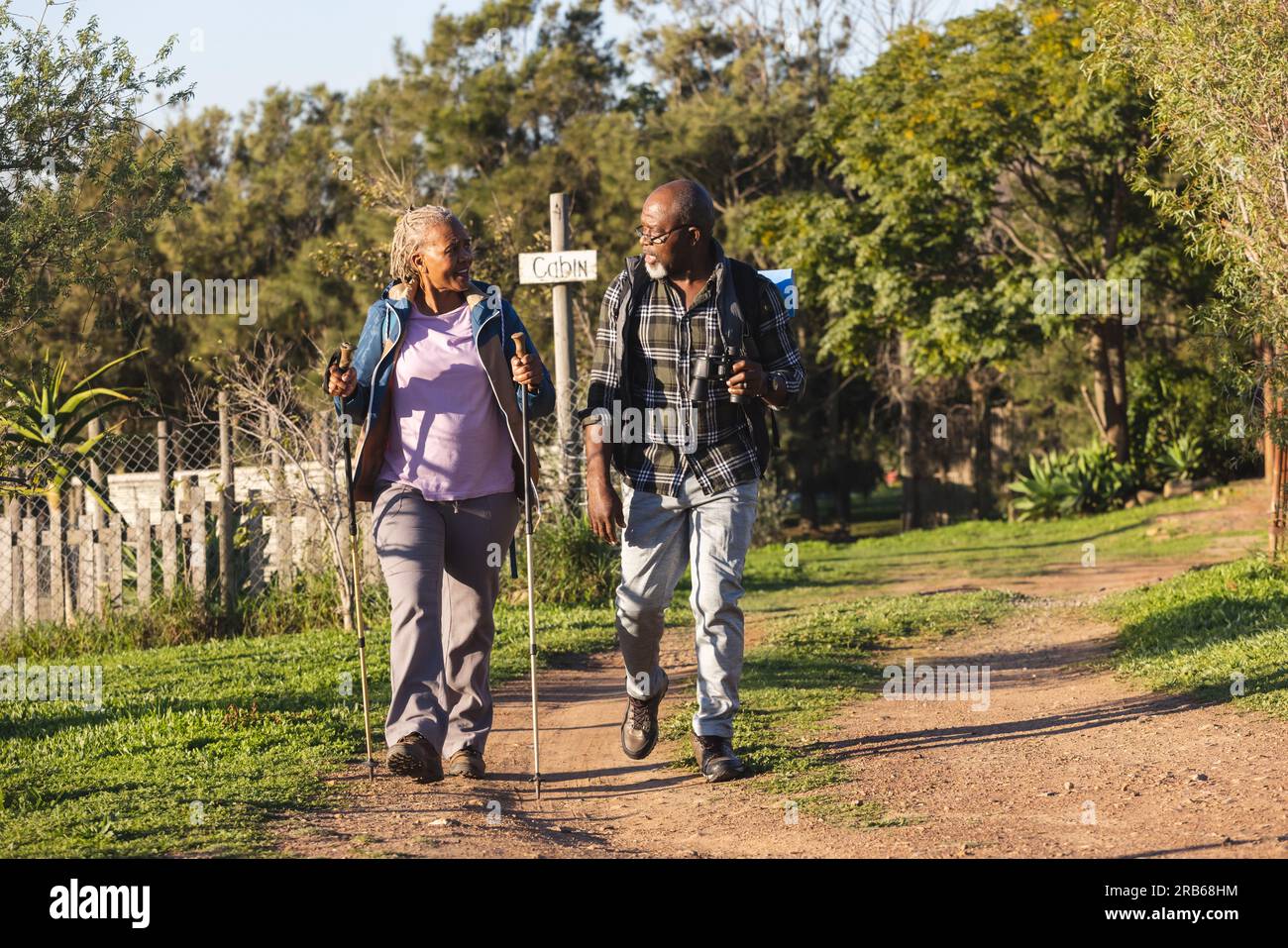 Happy senior african american couple with backpacks walking in sunny ...