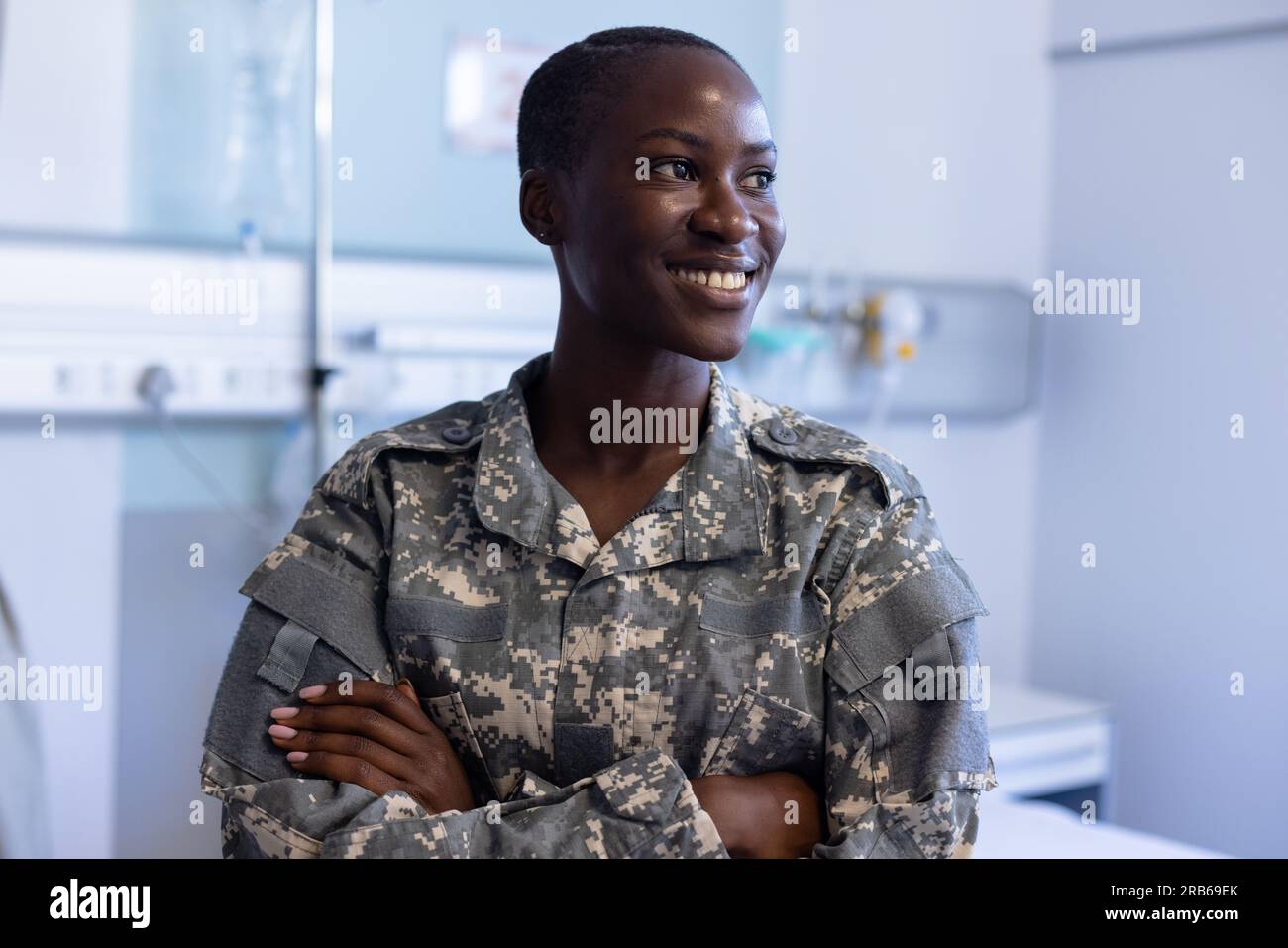 Happy african american female soldier wearing military uniform crossing arms at hospital. Hospital, medicine, healthcare, healthcare services and mili Stock Photo