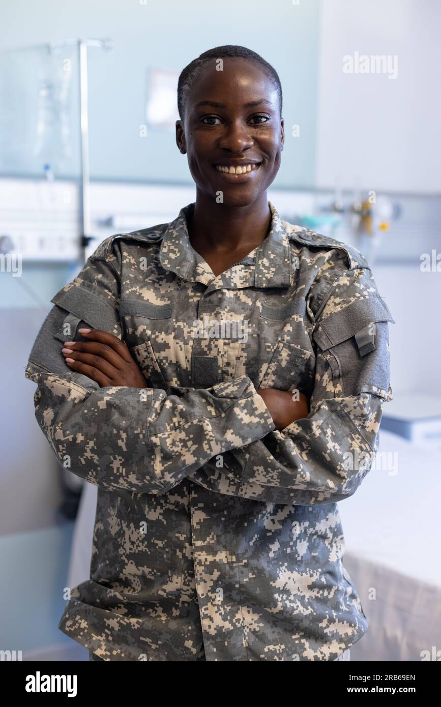 Portrait of happy african american female soldier wearing military uniform crossing arms at hospital. Hospital, medicine, healthcare, healthcare servi Stock Photo