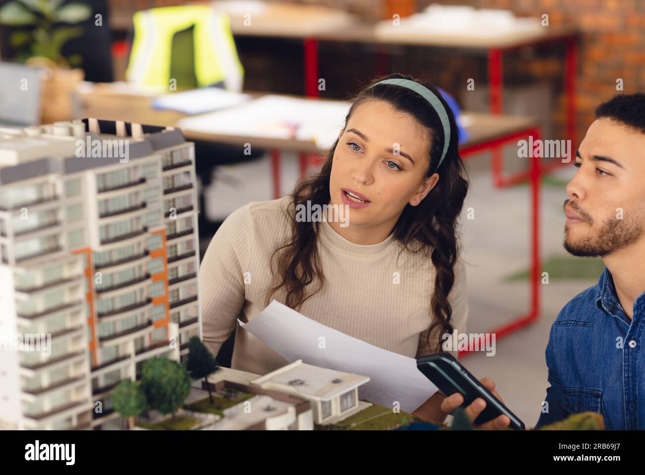 Diverse business people looking at architectural model and discussing work at office. Business, teamwork, architecture and design. Stock Photo
