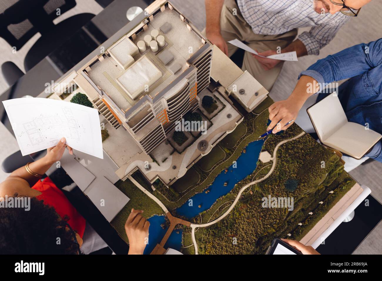Unalt Diverse business people looking at architectural plans and model ...