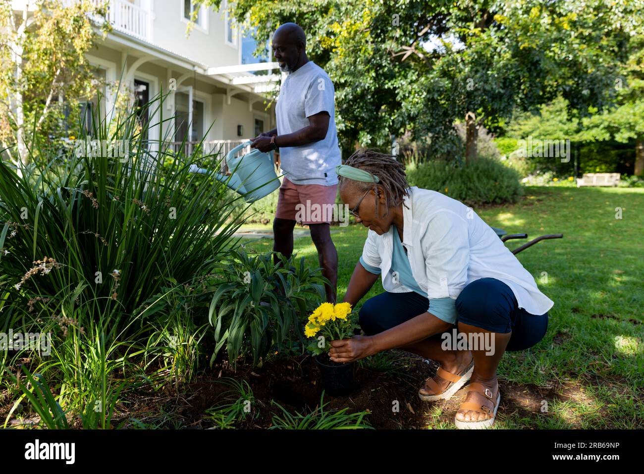 Happy african american senior couple tending to plants in sunny garden ...