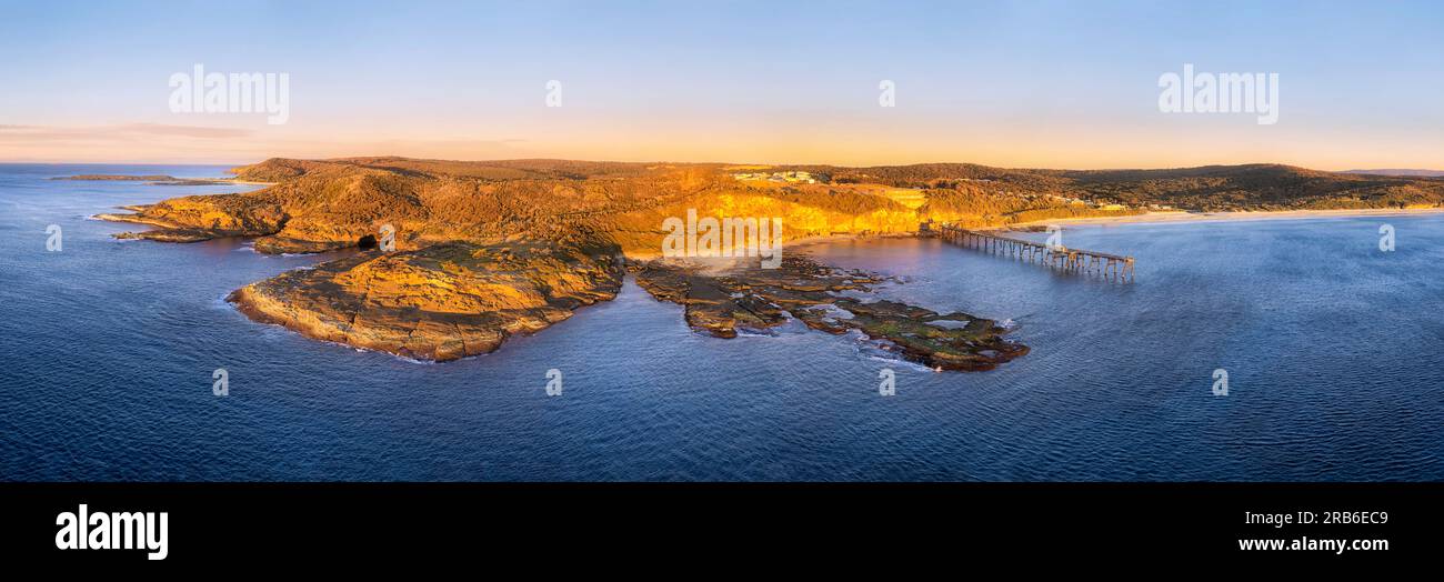 Sandstone rocky cape waterfront of Pacific ocean at Middle camp beach on Catherine Hill bay coast in Australia - aerial sunrise panorama. Stock Photo