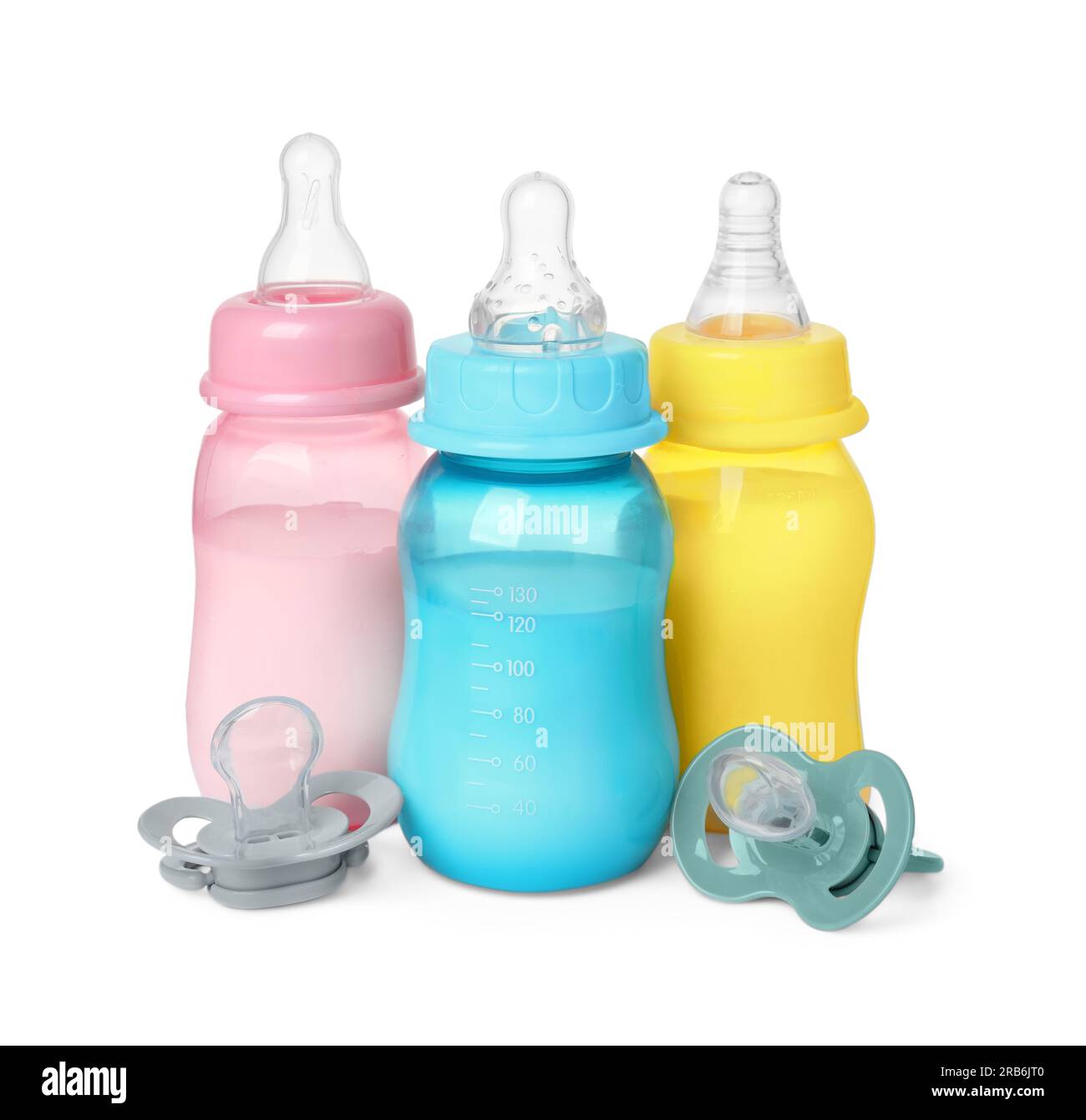 Feeding bottles with milk and pacifiers on white background Stock Photo