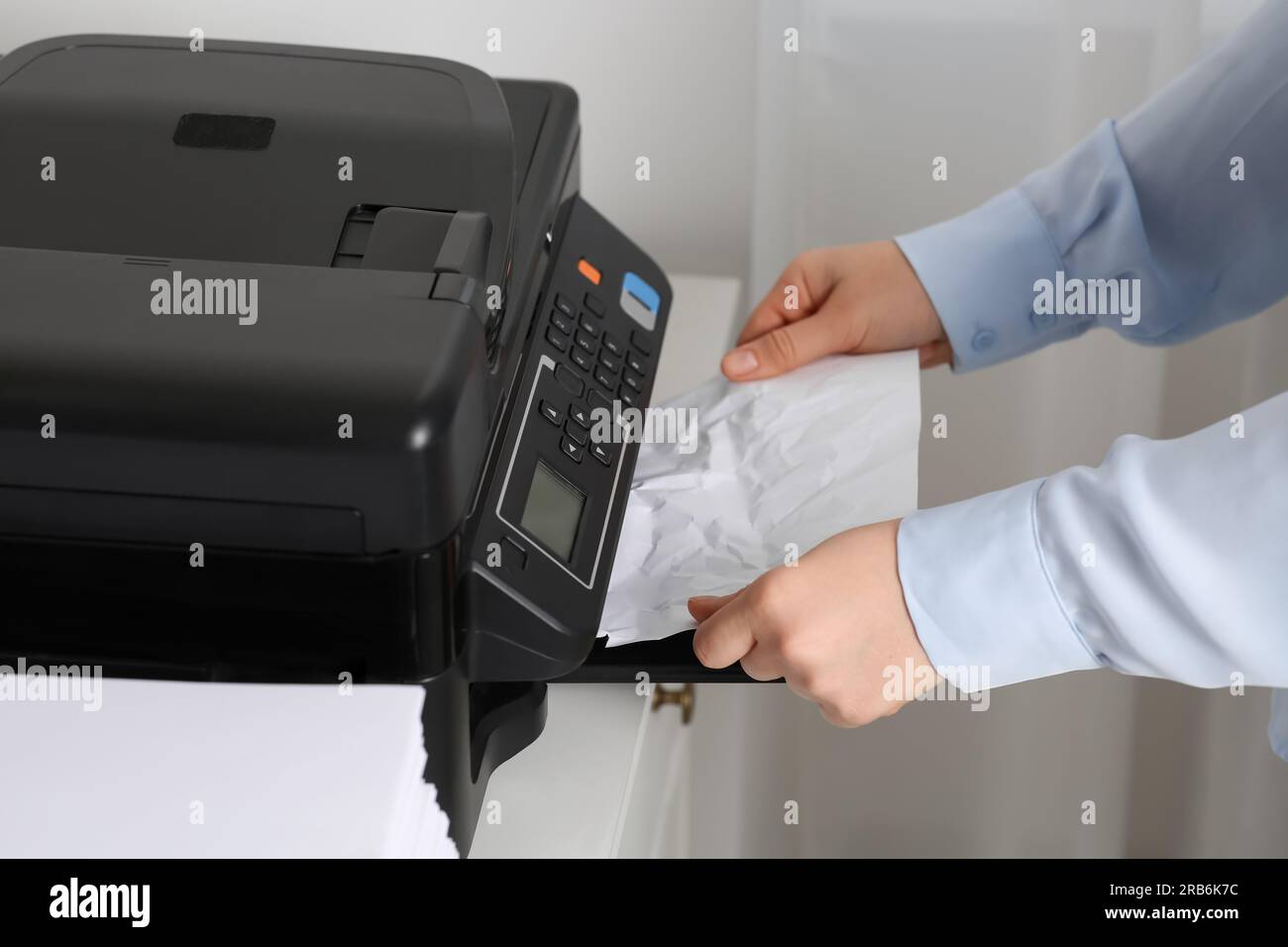 Woman taking crumpled paper out of printer indoors, closeup Stock Photo