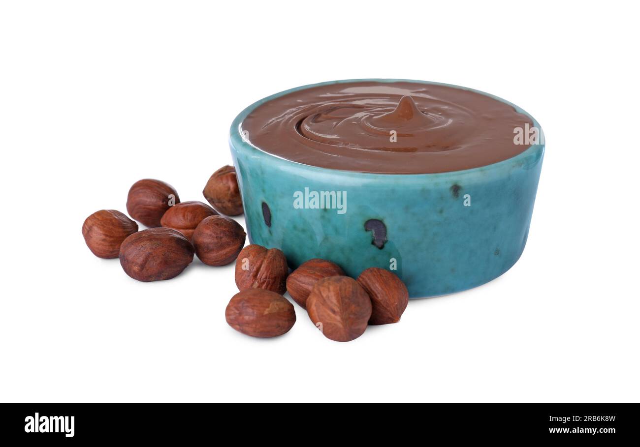 Bowl with delicious chocolate paste and hazelnuts on white background Stock Photo