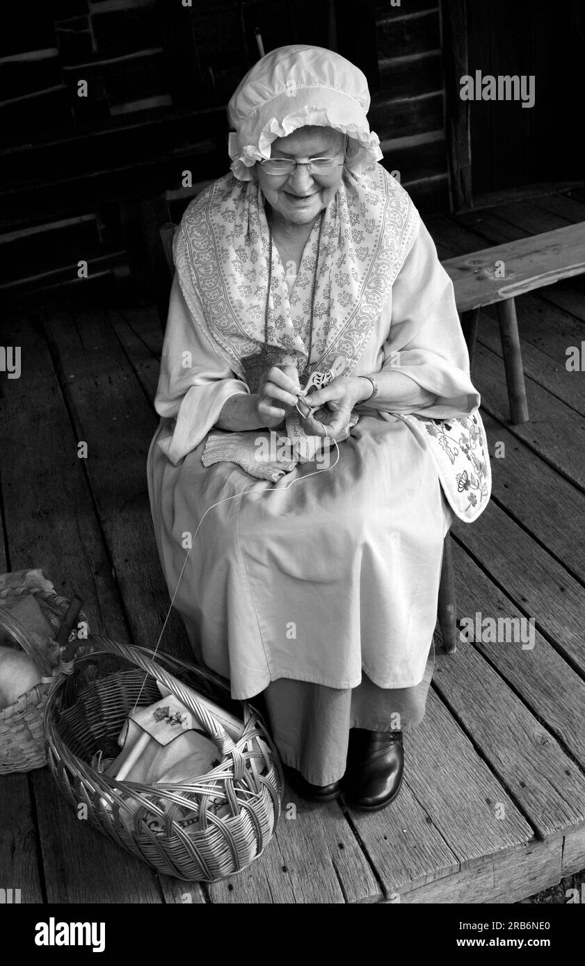 A 19th century pioneer reenactor talks with visitors while demonstrating early knitting techniques at a living history event in Abingdon, Virginia. Stock Photo