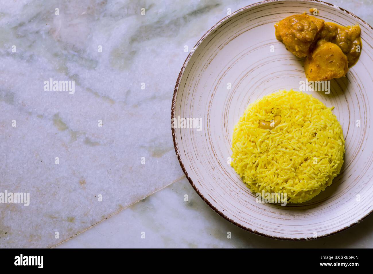 Pulav and potato curry served on a plate. Traditional Bengali basanti polao or sweet polao or fried rice served as offering to the deity during hindu Stock Photo