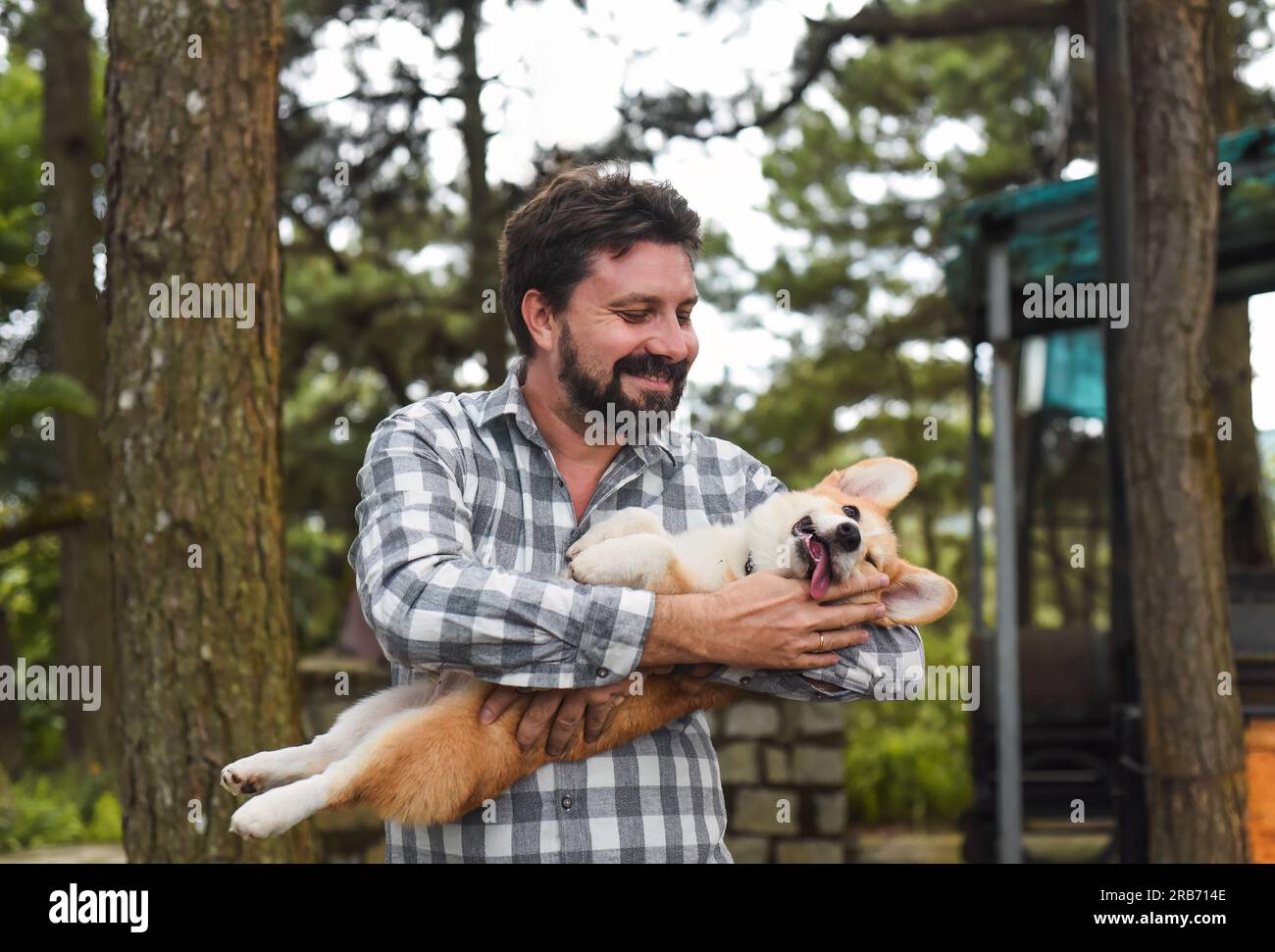 Happy bearded man holding his welsh corgi dog and smiles Stock Photo